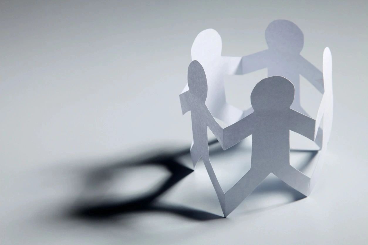 Paper cutout figures holding hands representing unity